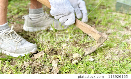 戴著工作手套、用單手鋤頭挖地的老婦人的手 戴著工作手套、用單手鋤頭挖地的老婦人的手 118926165