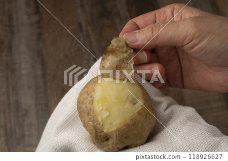 Potato peeling: Peel the skin off boiled potatoes by hand 118926627