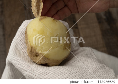 Potato peeling: Peel the skin off boiled potatoes by hand 118926629