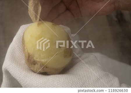 Potato peeling: Peel the skin off boiled potatoes by hand 118926630