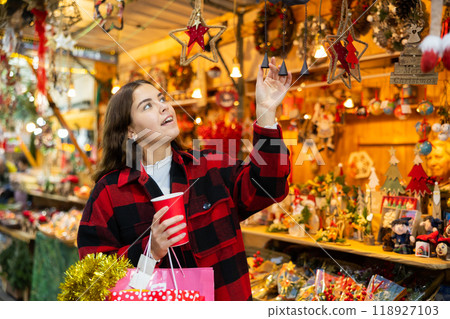 Girl with paper cup looking for decorations at Christmas market 118927103