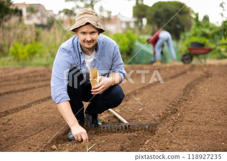 Guy is planting seeds in open ground 118927235