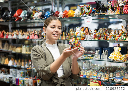 Young woman looking at bull figurine at souvenir market Young woman looking at bull figurine at souvenir market 118927252