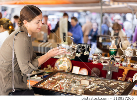 Young woman looking at antique basket at flea market 118927266