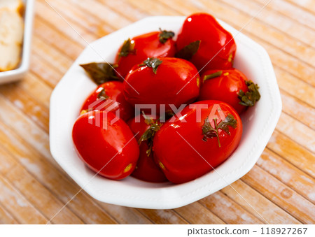 Canned tomatoes on white plate on wooden table 118927267