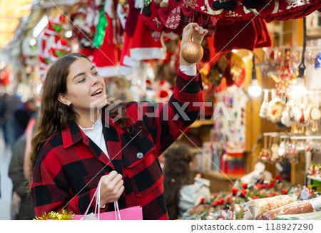 Smiling girl viewing golden bauble at street Christmas fair Smiling girl viewing golden bauble at street Christmas fair 118927290