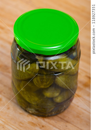 Glass jar with pickled cucumbers on wooden background 118927351
