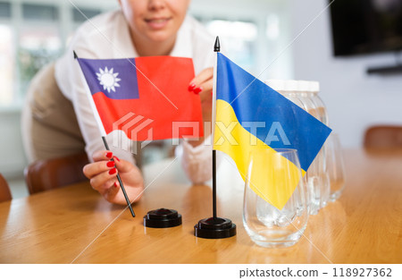 Woman setting flags of Ukraine and Taiwan on negotiating table 118927362