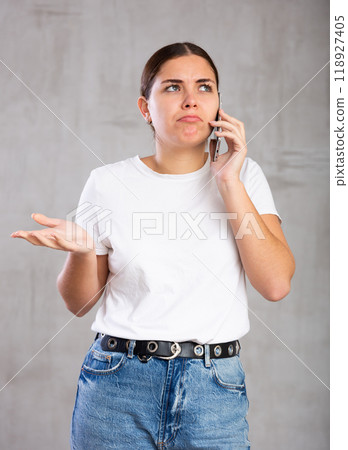 Surprised young woman talking on mobile phone Surprised young woman talking on mobile phone 118927405
