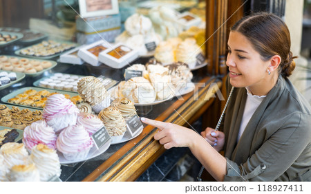 Young woman chooses sweet cupcake at confectionery shop 118927411