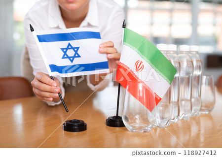 Little flag of Iran on table and flag of Israel put next to it by young woman 118927412