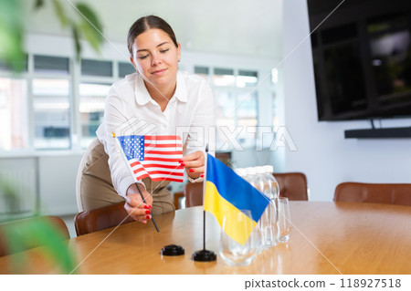 Young lady sets miniatures Ukrainian and American flag for international negotiations 118927518