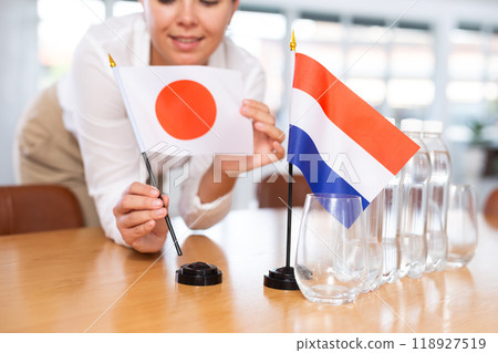 Blurry girl set midget flags of Netherlands and Japan before international negotiations 118927519