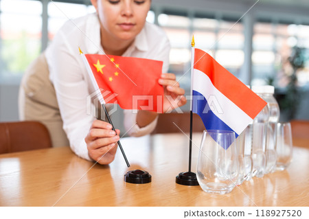 Blurry girl set midget flags of Netherlands and China before international negotiations 118927520