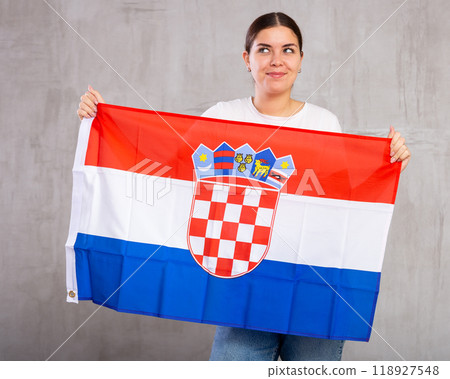 Joyous young woman holding Croatia flag against unicoloured background 118927548
