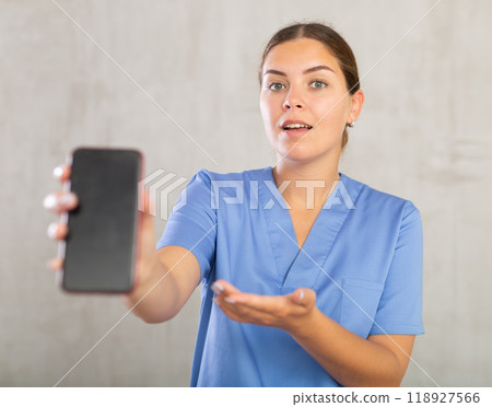 Young woman posing in medical uniform with phone Young woman posing in medical uniform with phone 118927566