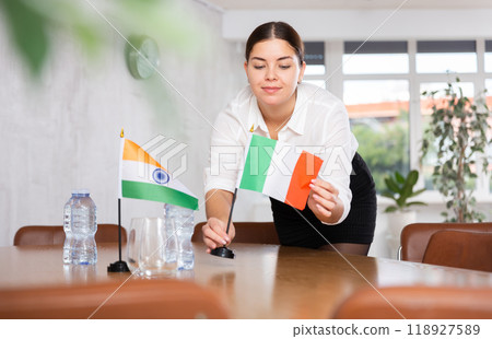 Young female attendant putting up flags for international negotiations between india and italy Young female attendant putting up flags for international negotiations between india and italy 118927589