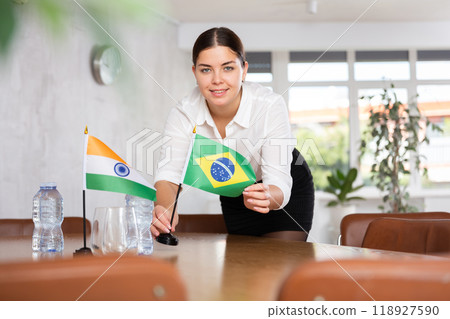 Employee of delegation prepares negotiating table - sets up flag of India and Brazilia Employee of delegation prepares negotiating table - sets up flag of India and Brazilia 118927590