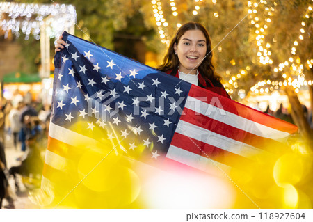Cheerful girl with American flag in city street Christmas fair Cheerful girl with American flag in city street Christmas fair 118927604