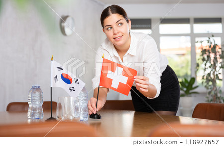 Young female attendant putting up flags for international negotiations between south korea and switzerland Young female attendant putting up flags for international negotiations between south korea and switzerland 118927657