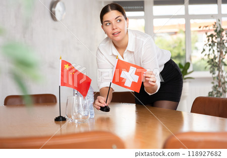 Young female attendant putting up flags for international negotiations between china and switzerland Young female attendant putting up flags for international negotiations between china and switzerland 118927682