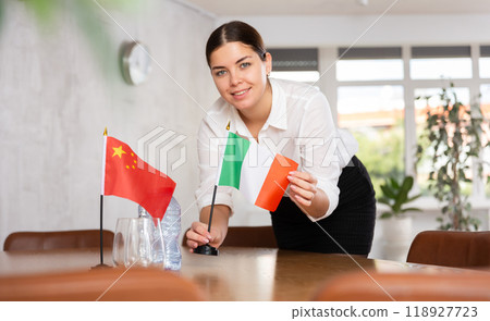 Young female attendant putting up flags for international negotiations between china and italy Young female attendant putting up flags for international negotiations between china and italy 118927723