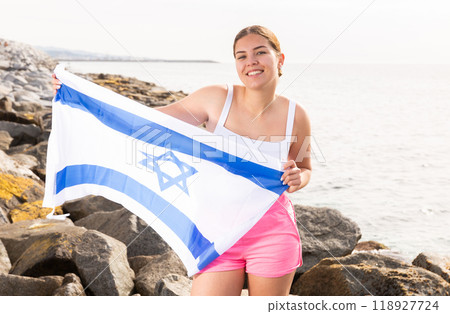 Young woman on coast posing with flag of Israel Young woman on coast posing with flag of Israel 118927724