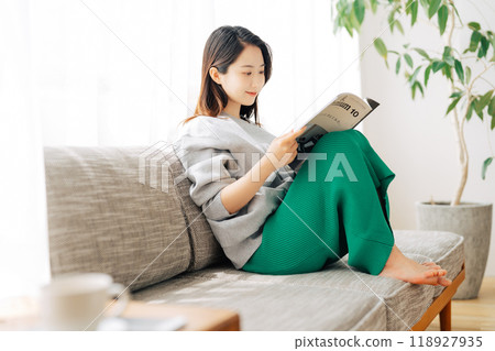 一個坐在沙發上看雜誌的女人 118927935
