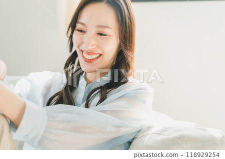 A woman in her 30s relaxing on the sofa in the living room 118929254
