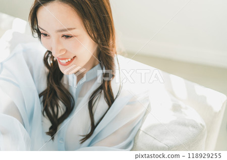 A woman in her 30s relaxing on the sofa in the living room 118929255