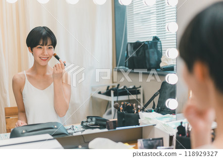 A young female model applying makeup in a makeup room 118929327