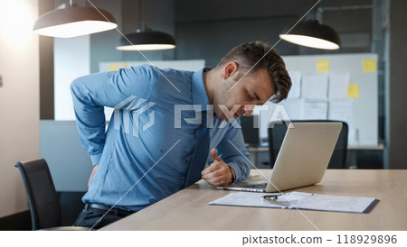 Back pain Male office employee, lower back pain while working at desk, potential chronic condition from sitting too long, needing ergonomic intervention, discomfort from poor posture, workplace 118929896