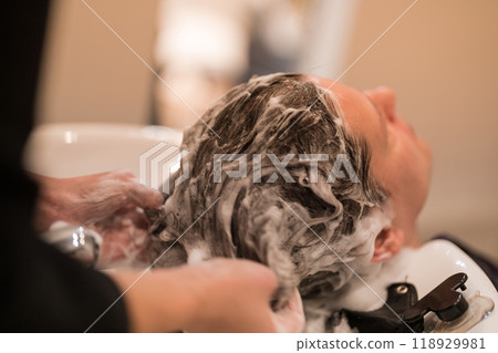 A hairdresser shampooing a male customer's hair A hairdresser shampooing a male customer's hair 118929981