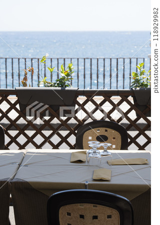 Table setting on the terrace with a sea view Table setting on the terrace with a sea view 118929982