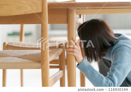 一個女人躲在桌子下面 118930194