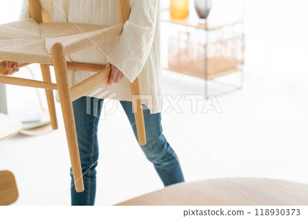 Woman moving a chair in the living room Woman moving a chair in the living room 118930373