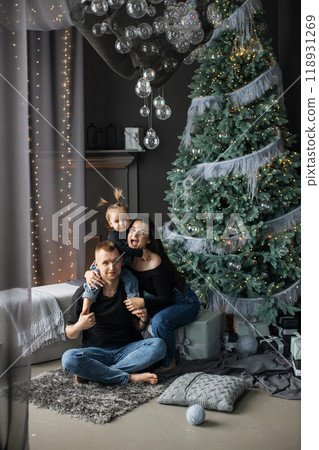 Happy family celebrating Christmas by their decorated tree Happy family celebrating Christmas by their decorated tree 118931269