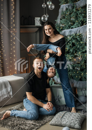 Happy family playing together by Christmas tree at home Happy family playing together by Christmas tree at home 118931279