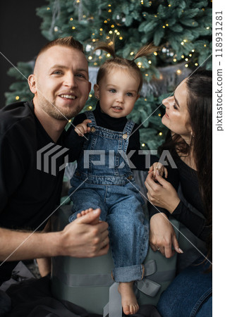 Family enjoying Christmas together by the tree indoors Family enjoying Christmas together by the tree indoors 118931281