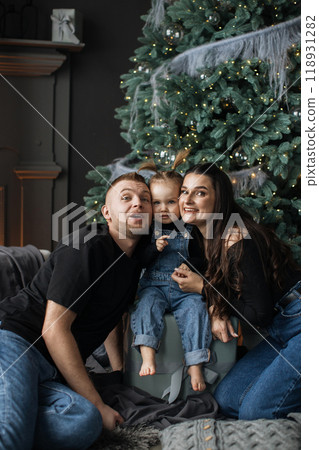 Happy family celebrating Christmas with toddler by Christmas tree 118931282
