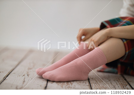 The feet of a young woman putting on socks 118932429