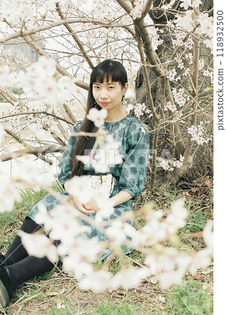一位女士在櫻花樹下擺姿勢，鏡子周圍環繞著櫻花 118932500