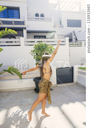 A Joyful Woman Happily Dancing Outdoors in Her Stylish Attire Beneath Bright Sunlight 118932665