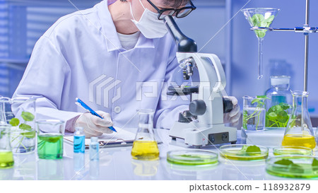 A scientist meticulously examines a centella sample under a microscope, carefully taking notes on a clipboard. Surrounding the microscope are various laboratory equipment and specimens in modern lab. A scientist meticulously examines a centella sample under a microscope, carefully taking notes on a clipboard. Surrounding the microscope are various laboratory equipment and specimens in modern lab. 118932879