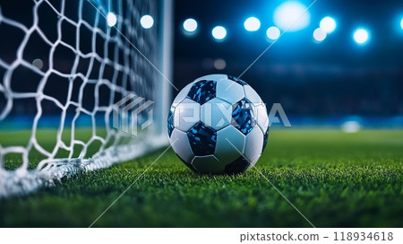 A close-up of a soccer ball near the goalpost, showcasing the excitement of a night game illuminated by bright stadium lights. 118934618