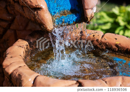 A decorative fountain featuring water flowing beautifully from a blue pipe 118936506