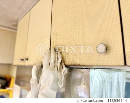 Two hands wearing vinyl gloves cleaning old kitchen cabinets Two hands wearing vinyl gloves cleaning old kitchen cabinets 118936544