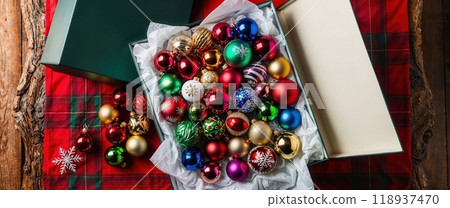Christmas baubles resting in box on table with wrapping paper 118937470