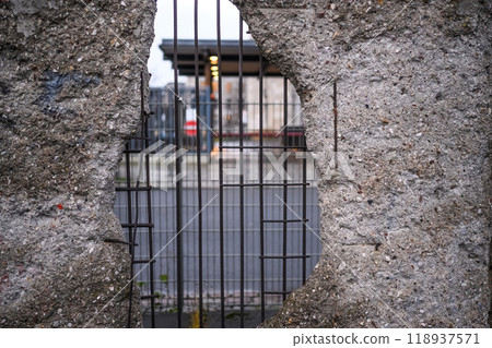 Hole in Broken Berlin wall and walking person against 118937571