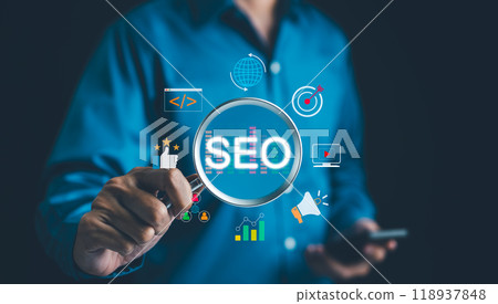 SEO Search Engine Optimization Concept. Businessman hold magnifying glass focuses highlighting SEO, surrounded by various digital marketing icons, representing search engine optimization strategies. 118937848